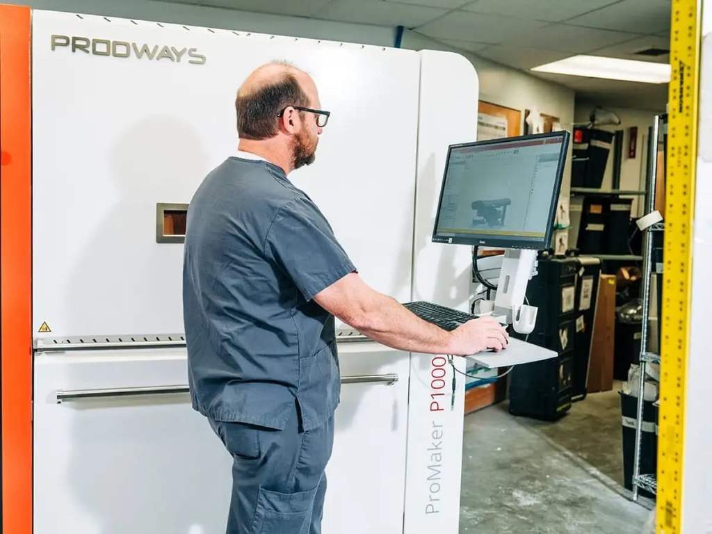 UAB Amputee Clinic employee working on computer with 3D-printed prosthetic technology